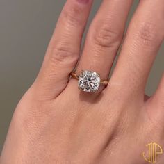 a woman's hand with a diamond ring on top of her finger, showing the center stone