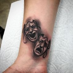 a tattoo with two masks on the wrist