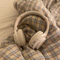 headphones laying on top of a bed with a plaid comforter and pillow in the background