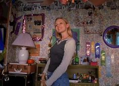 a woman standing in front of a room filled with clutter