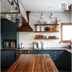 a kitchen with blue cabinets and wooden counter tops, white subway tile backsplash