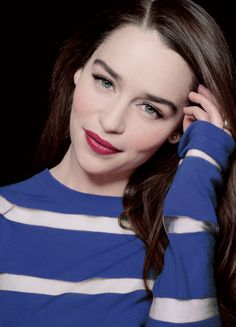 a woman with long brown hair wearing a blue and white striped sweater posing for a photo