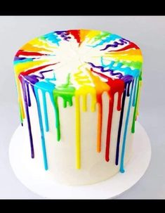 a multicolored cake with dripping icing on it