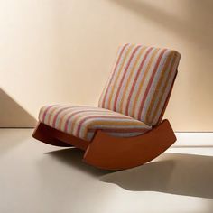 a striped chair sitting on top of a floor next to a wall with a window