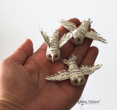 three small birds made out of book pages in the palm of someone's hand