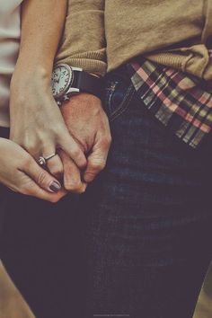 two people holding hands with rings on their fingers and one person wearing a plaid shirt