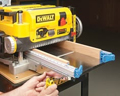 a man is using a table saw to cut wood with a router on it