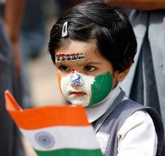 a young boy with his face painted in the colors of india and green, white and orange