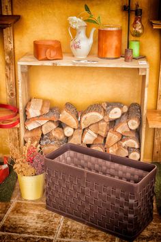 a fire place with logs and baskets on the shelf next to it in front of a yellow wall