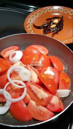 tomatoes and onions being cooked in a frying pan