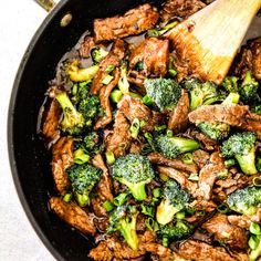 beef and broccoli stir fry in a skillet with a wooden spatula