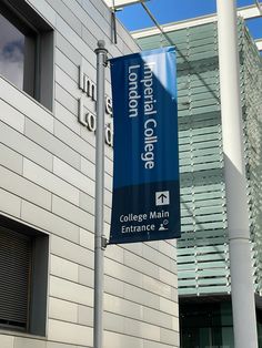 a large blue sign hanging from the side of a building next to a tall white pole