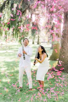 a man and woman standing under a tree with confetti in front of them