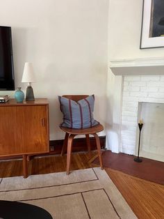 a living room with a television, chair and fireplace