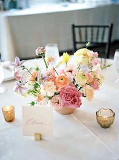 a vase filled with lots of flowers on top of a table next to two candles