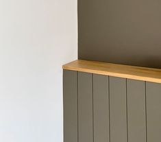 a wooden shelf sitting on top of a white wall next to a gray painted wall