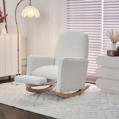 a white rocking chair sitting on top of a rug