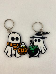 two halloween themed key chains with ghost and pumpkins on them, one holding a black bag