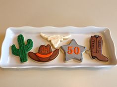 decorated cookies in the shape of cowboy's hats and boots on a white platter