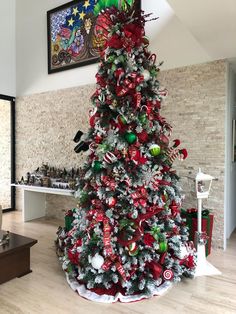 a decorated christmas tree in the middle of a living room with red and green decorations