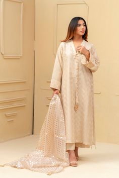 Expertly crafted from luxurious khaadi silk, this beige shalwar kameez boasts a stunning jamawar mesore dupatta and silk trousers. The hand sewn pearl details on the sleeves and neckline add a touch of elegance to this traditional ensemble. Elevate your style with this timeless piece. 3-Piece Suit Elegant Semi-stitched Silk Sherwani, Festive Slub Silk Kurta With Naqshi Detail, Festive Slub Silk Salwar Kameez With Naqshi, Unstitched Beige Sherwani With Naqshi Detailing, Festive Naqshi Slub Silk Salwar Kameez, Elegant Silk Sherwani With Naqshi Detailing, Elegant Chanderi Sherwani For Formal Occasions, Elegant Sherwani With Sheer Dupatta For Eid, Elegant Formal Chanderi Sherwani