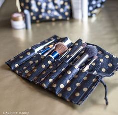 a polka dot purse with makeup brushes in it on a table next to other items