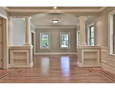 an empty room with wood floors and columns