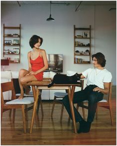 a woman sitting at a table with a cat on her lap next to a man