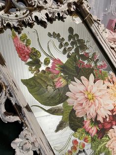 an ornate frame with flowers painted on the glass in front of it is sitting on a table