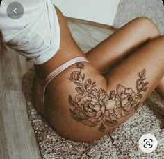 a woman laying on the floor with her stomach covered in flowers and leaves tattoo design