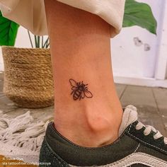 a woman's foot with a small bee tattoo on the left side of her ankle