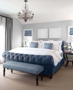 an image of a bedroom setting with blue and white colors on the bed, chandelier