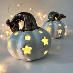 two ceramic pumpkins with lights on them sitting on a table next to each other