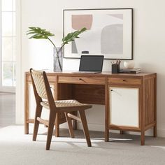 a wooden desk with a laptop on top of it next to a chair and potted plant