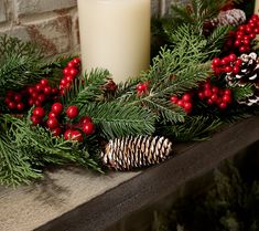 a candle and some pine cones on a mantle