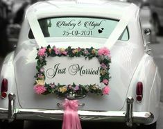 a wedding car decorated with pink flowers and greenery