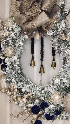 a wreath with bells and ornaments hanging on the front door