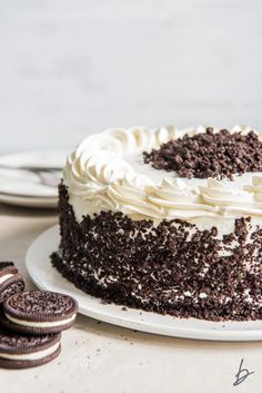 a chocolate cake with white frosting and oreo cookies on the side next to it