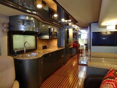 a kitchen and living room inside of a bus with wood flooring on the side