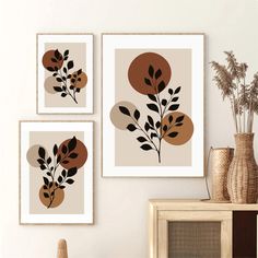 three framed art pieces on the wall above a dresser and vase with flowers in it