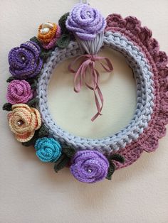 a crocheted wreath with flowers hanging on the wall