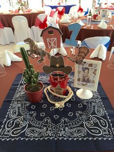 a table topped with a bandana covered table cloth and cactus in front of it