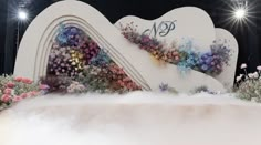 an artistic display with flowers and clouds in the air on top of a cloud filled stage