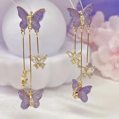 two purple butterflies are hanging from gold ear pins