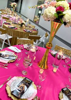 a pink table cloth topped with plates and vases filled with white and pink flowers