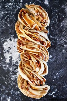 an overhead view of some food on a black surface with white icing and pecans