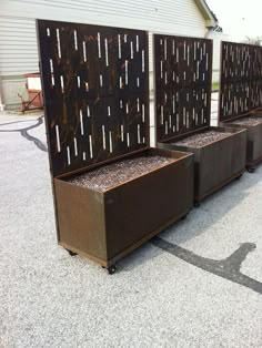 three metal planters sitting next to each other on top of a cement ground near a building