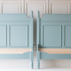 two blue beds side by side with wooden slats on the headboard and foot boards