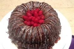 a chocolate cake topped with raspberries on top of a white plate