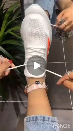 two people tying up their shoes on a rope in front of a potted plant